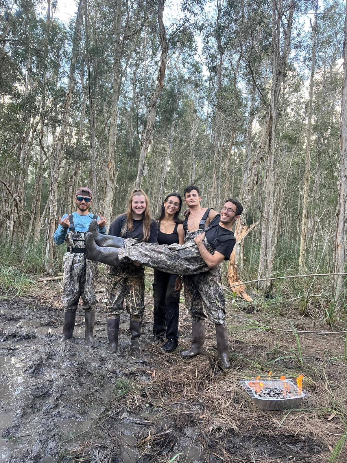 Group of muddy riders posing together in the woods