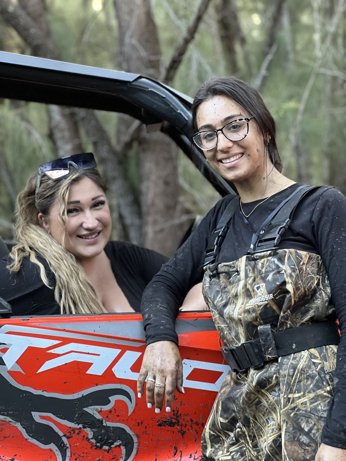 Two women posing next to a red ATV