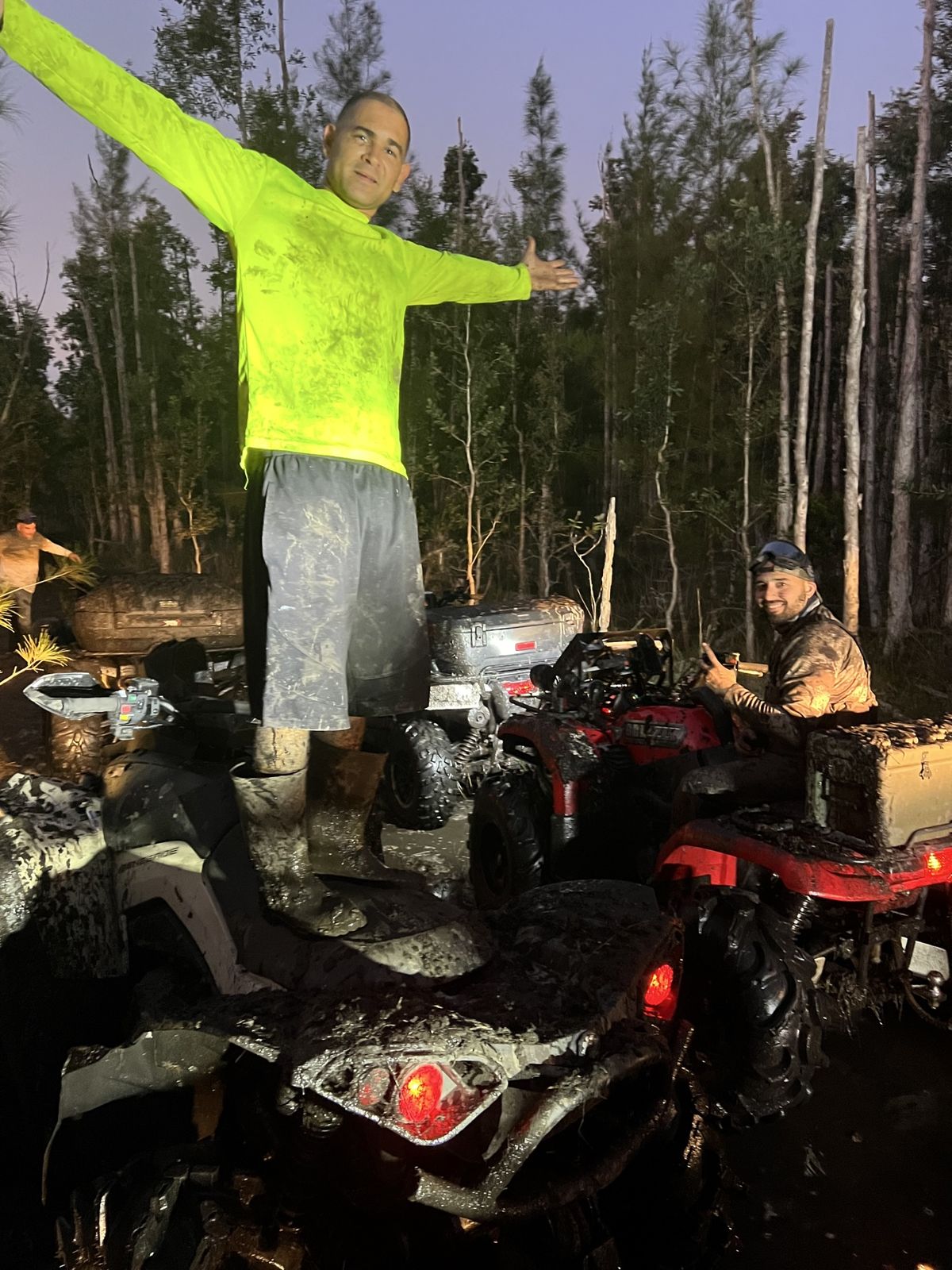 Rider in a neon shirt standing on an ATV at night