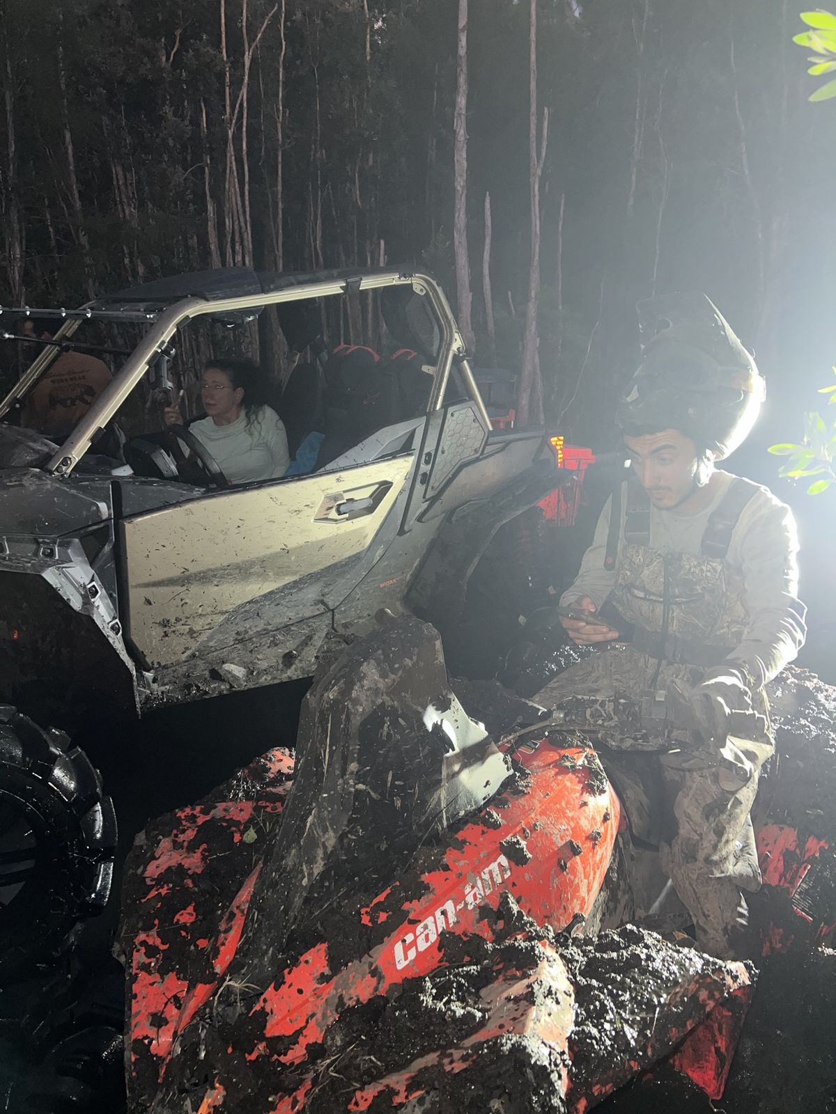 Couple smiling inside a muddy SXS at night