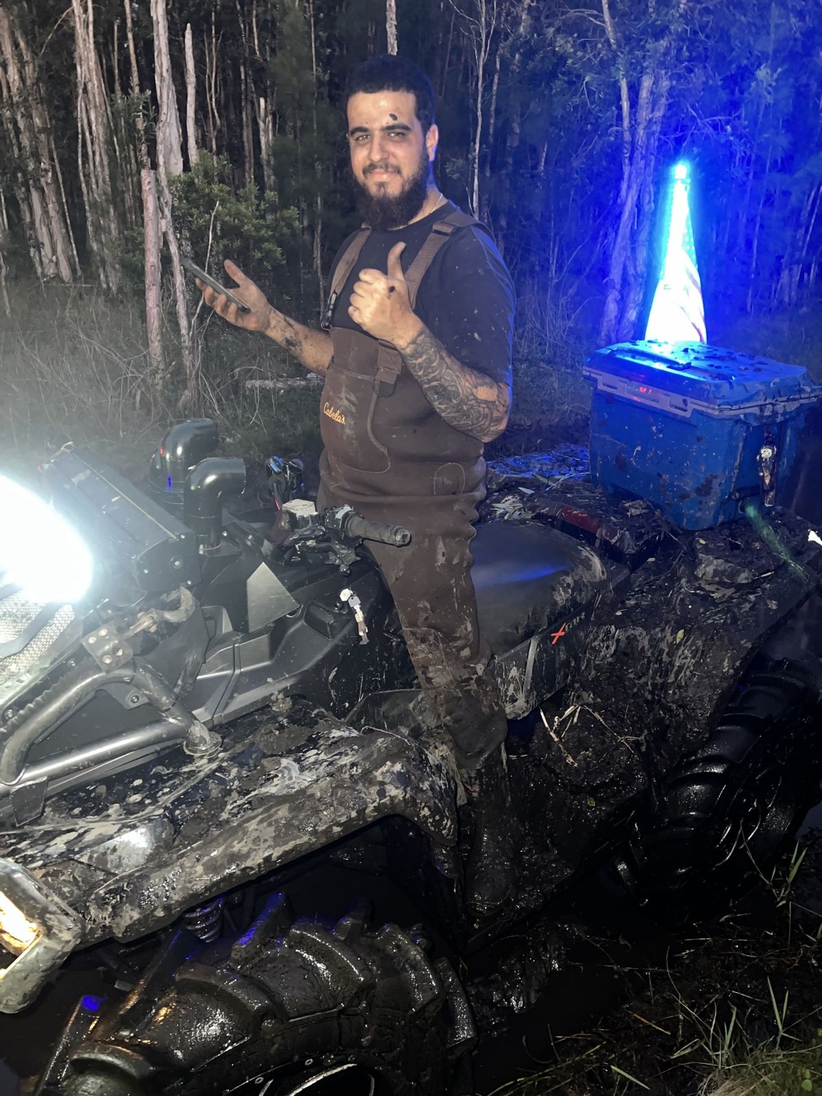 Rider next to an ATV with blue lights at night