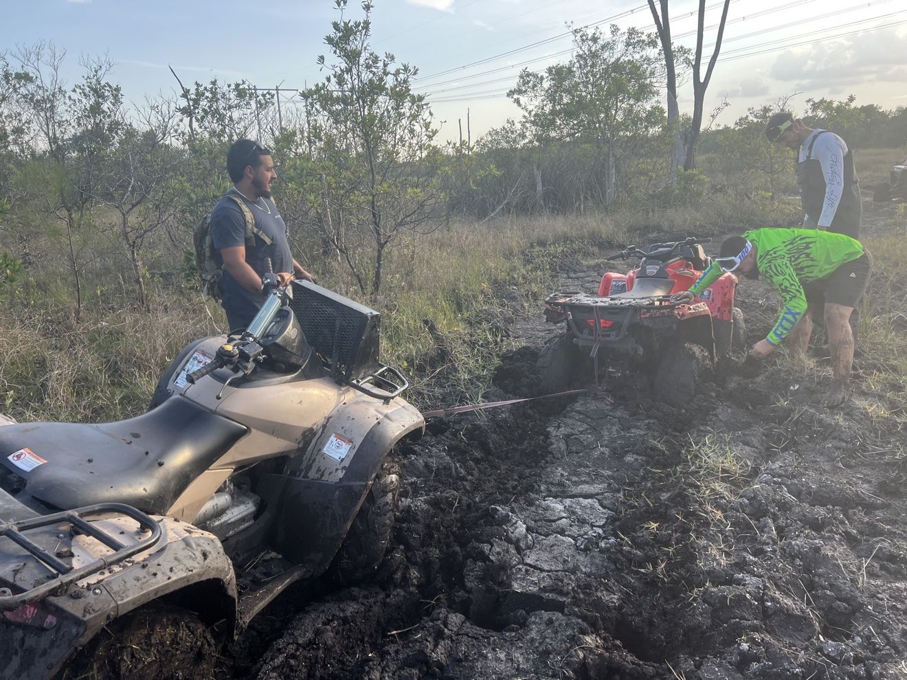 Riders pulling an ATV out of deep mud