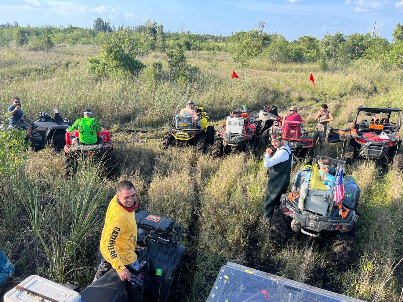 Lineup of muddy ATVs and riders in a field