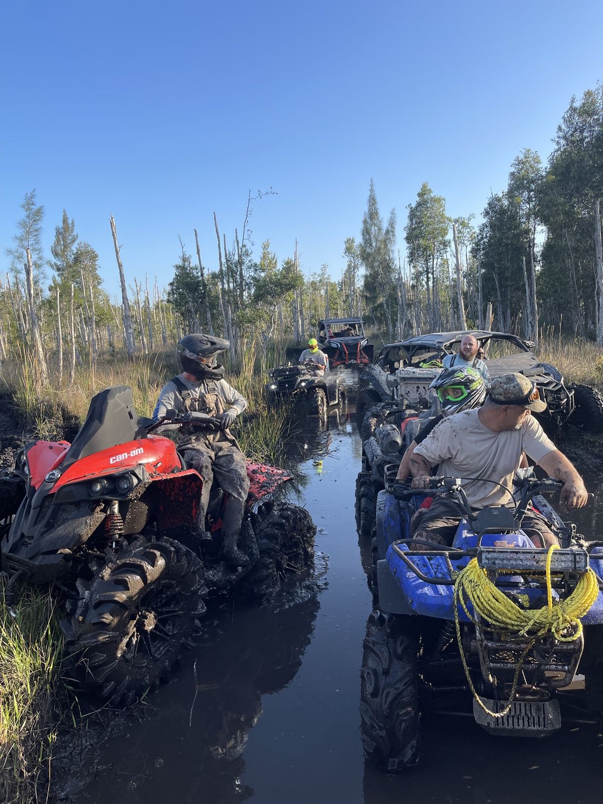 Convoy of ATVs riding through a water trail