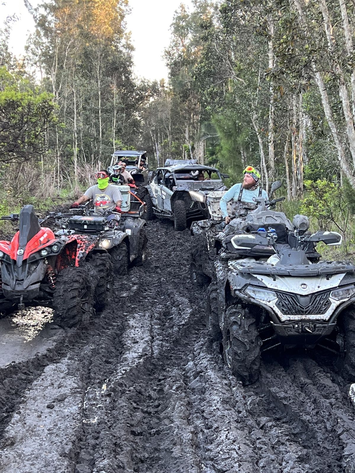 Convoy of ATVs on a muddy trail