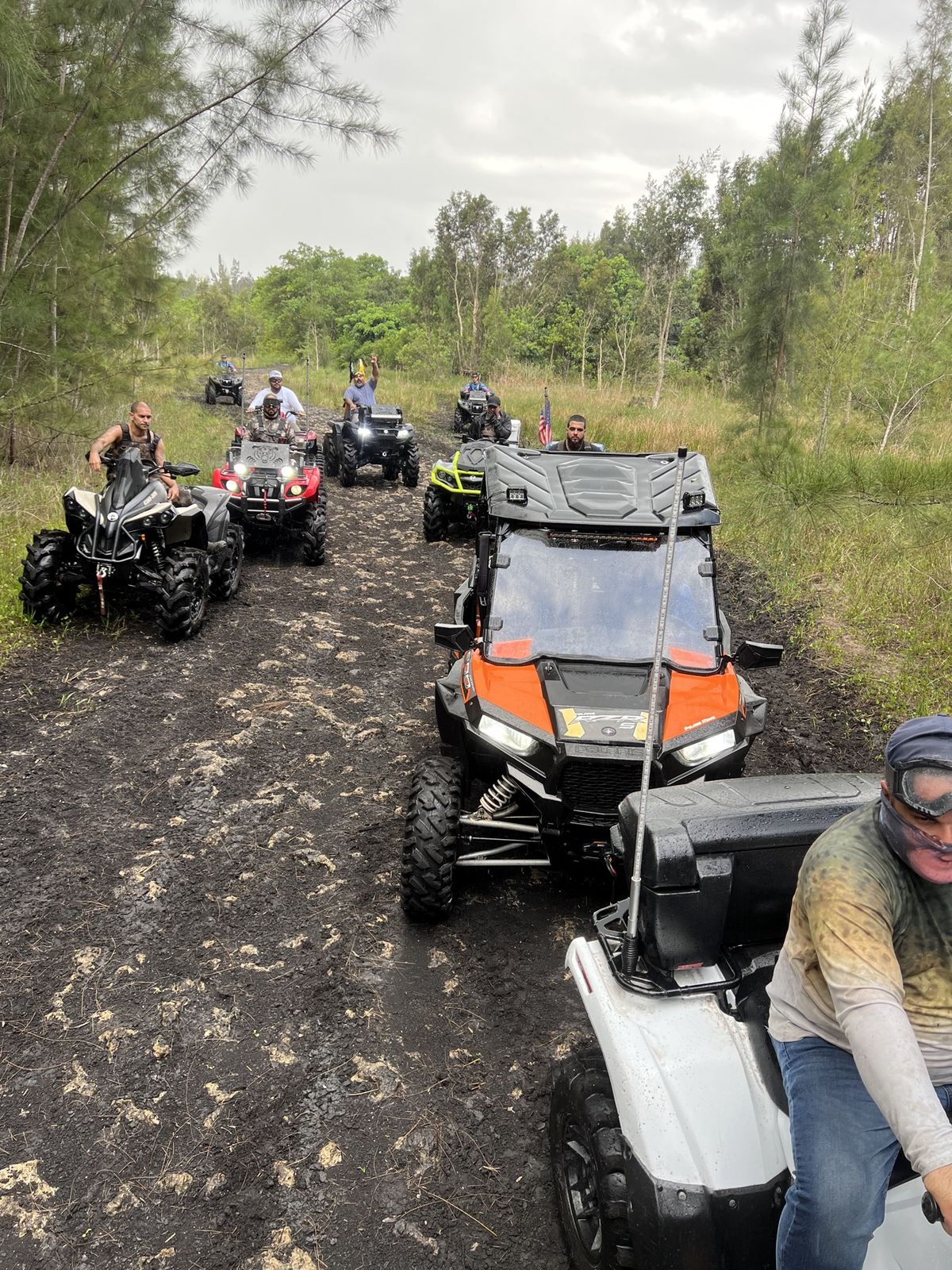 Convoy of ATVs on a muddy trail