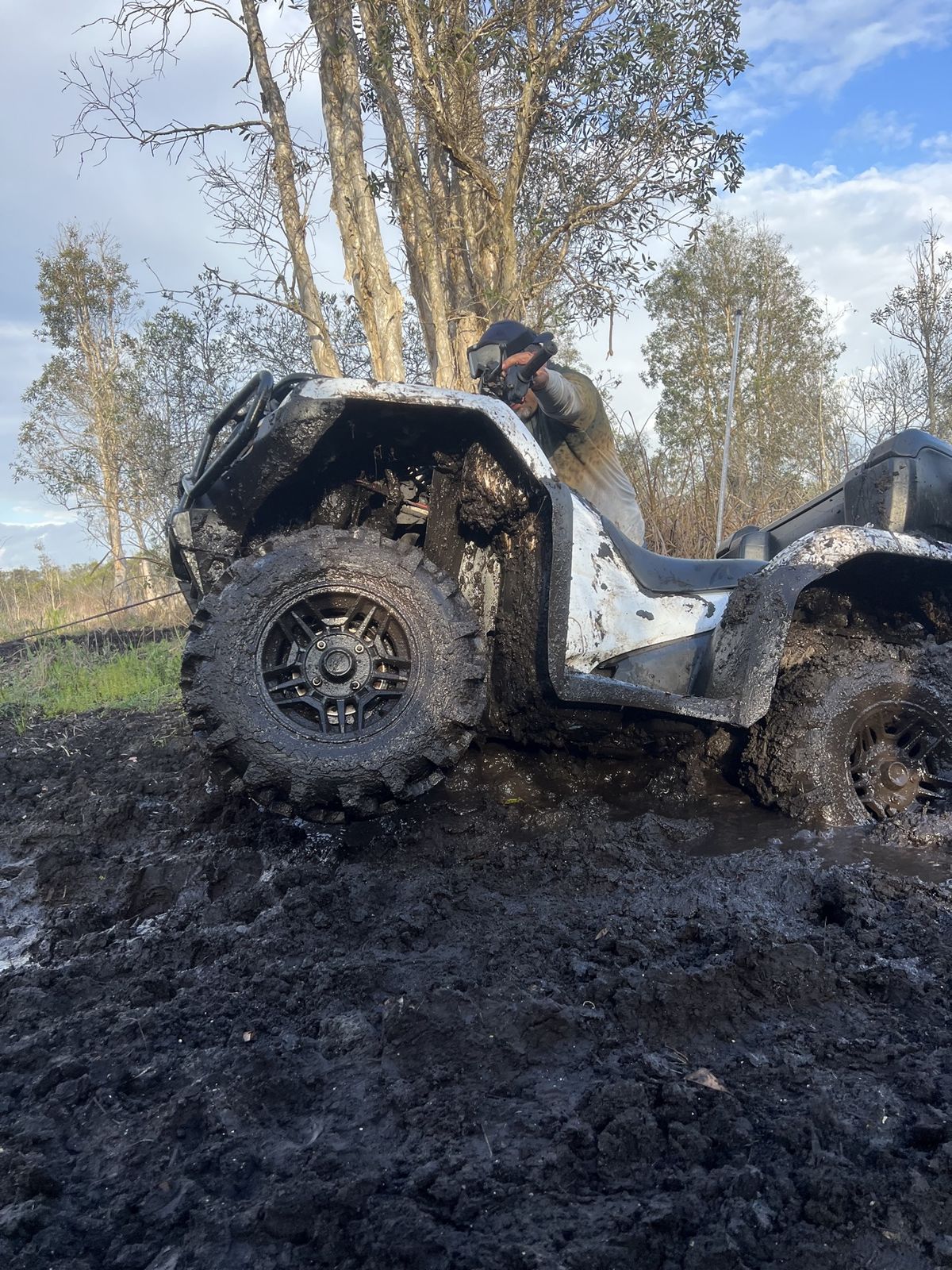 Group of riders and ATVs on a muddy trail