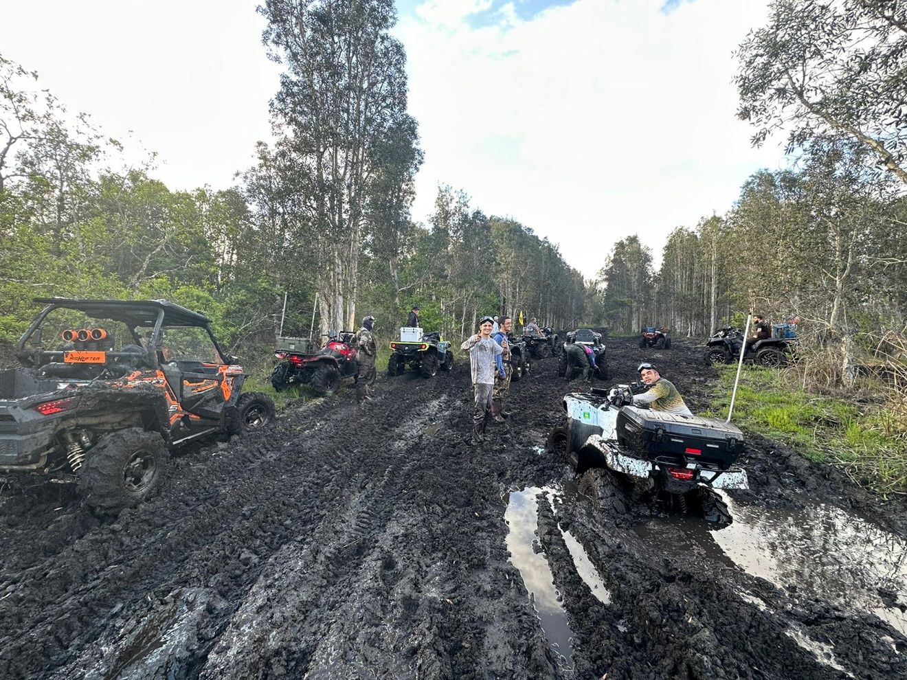 Convoy of ATVs riding through a flooded trail