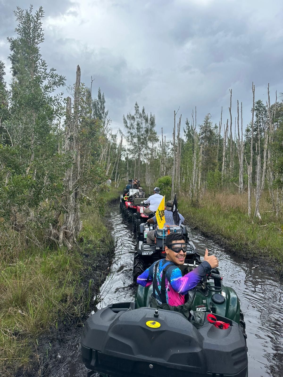 Convoy of ATVs riding through a flooded trail