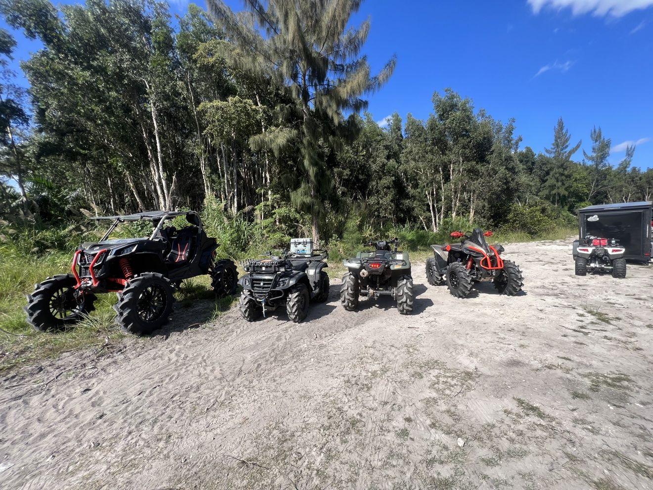 Lineup of ATVs and SXSs at a sandy staging area