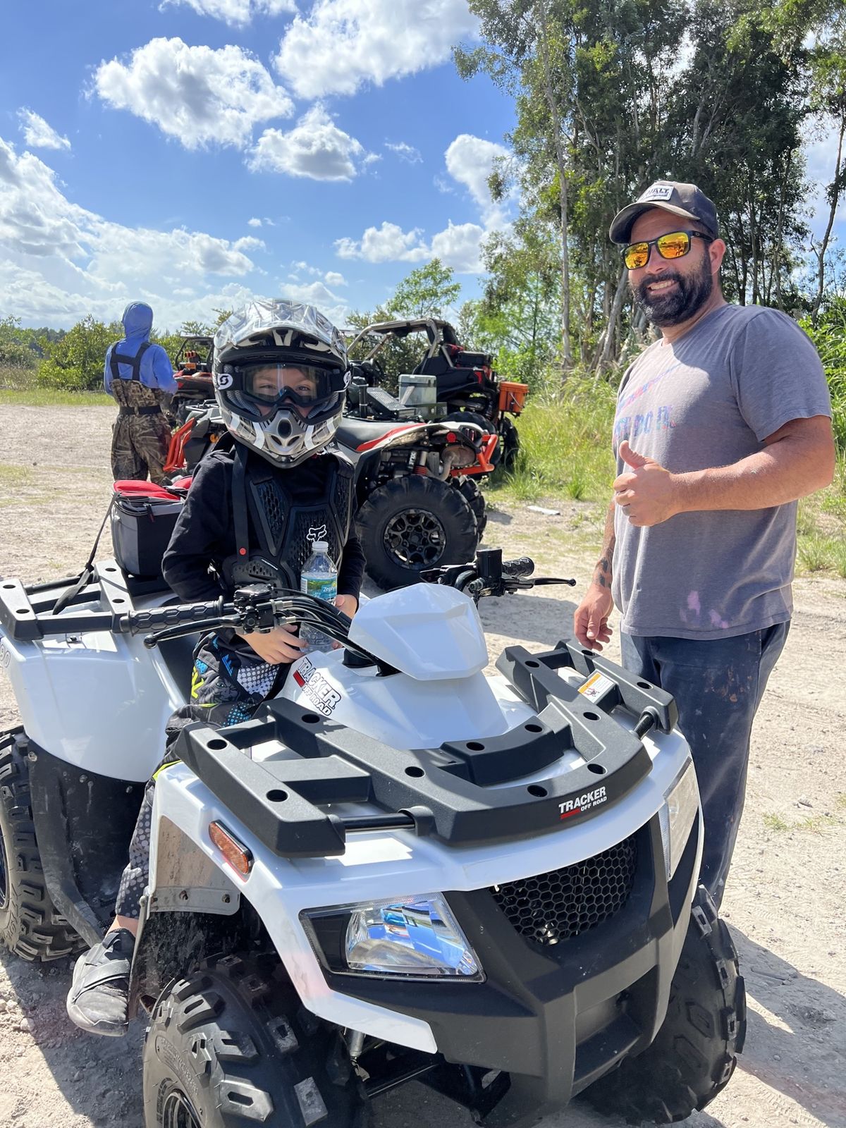 Rider standing next to a white ATV