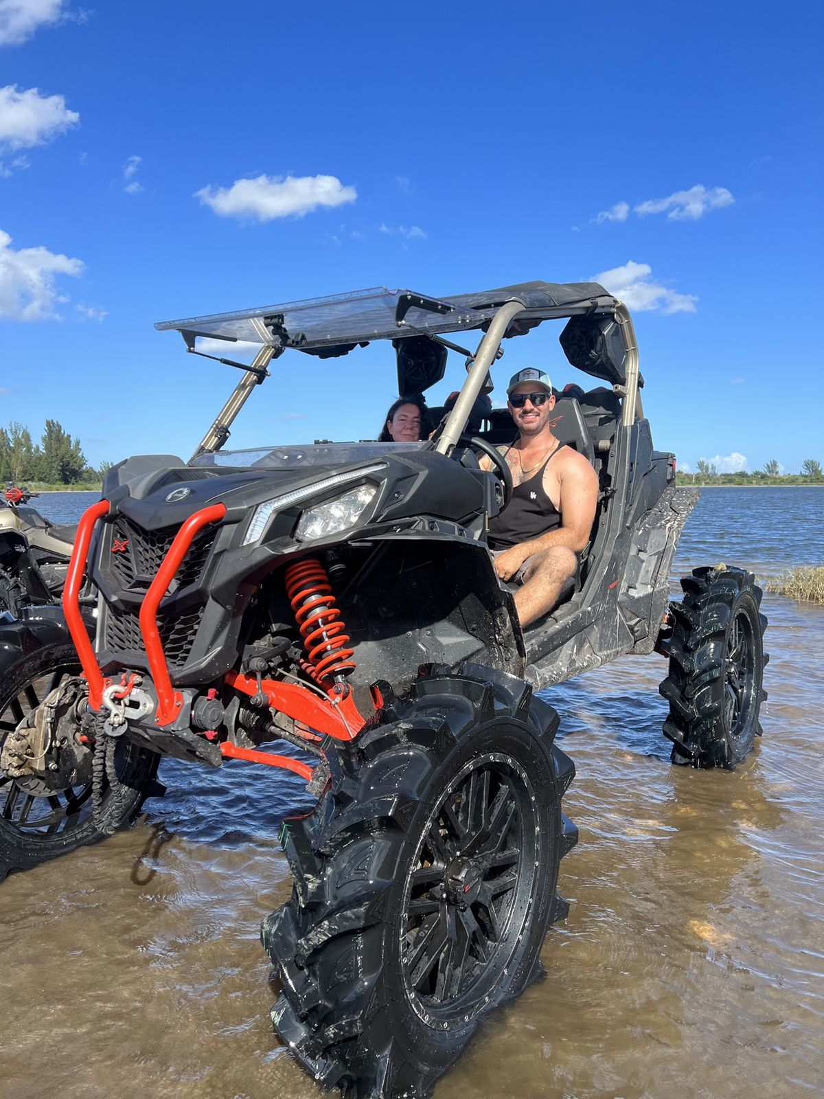 Orange SXS driving through a water trail