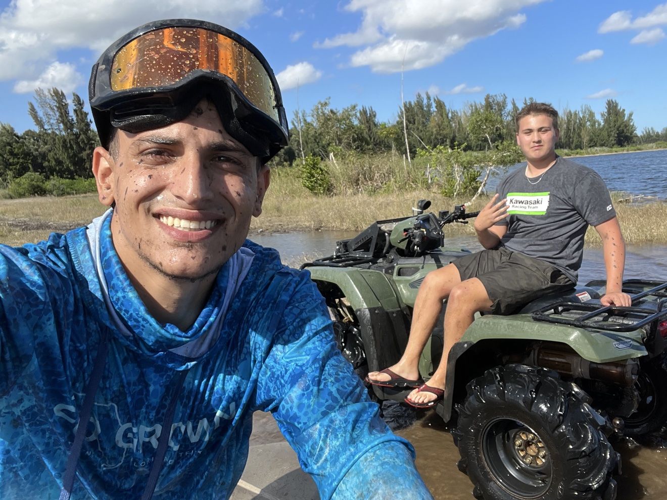 Rider selfie next to a friend on a green ATV