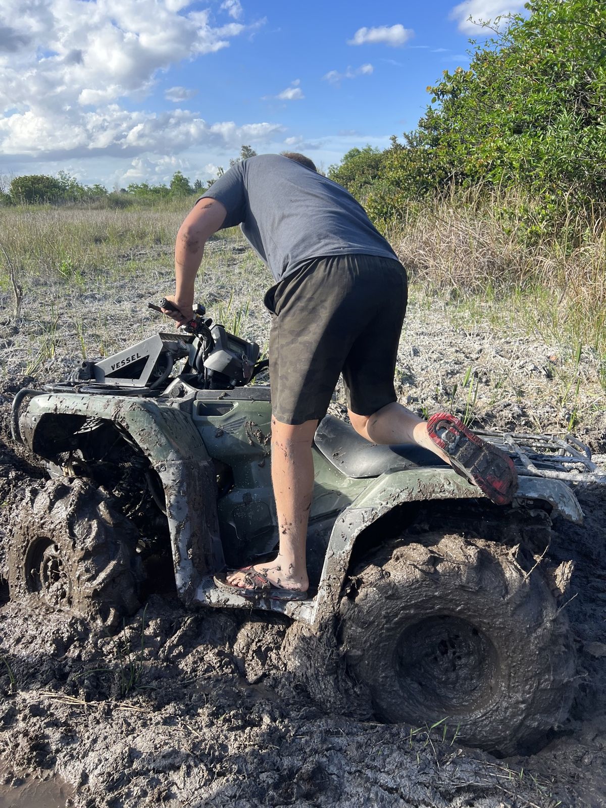 Rider climbing onto a muddy ATV