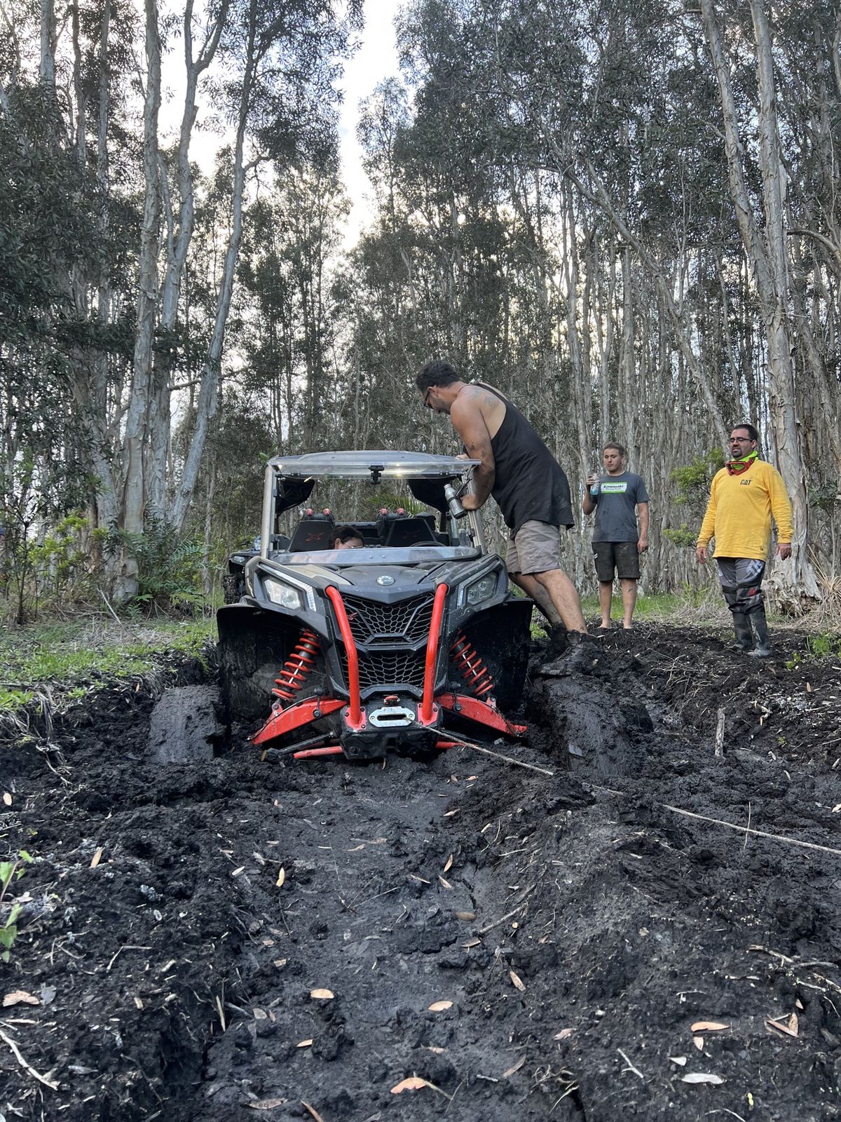 Group of riders pulling a SXS out of the mud