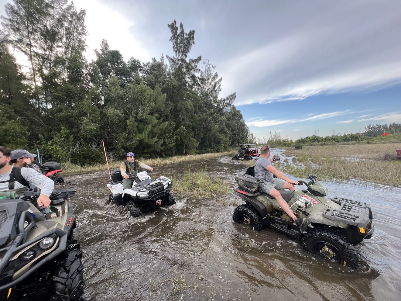 Riders crossing a water trail on ATVs