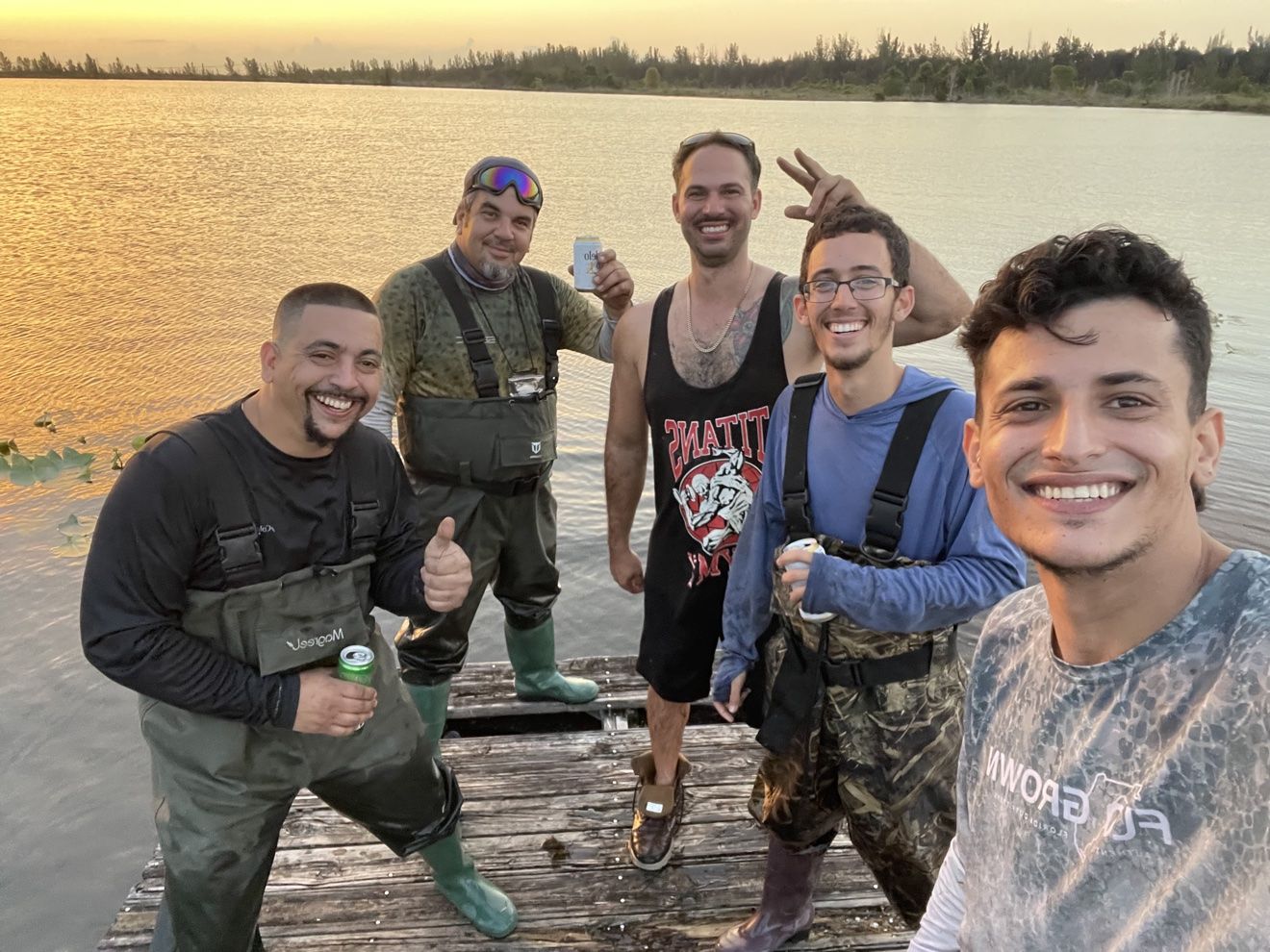 Group selfie of riders on a dock at sunset