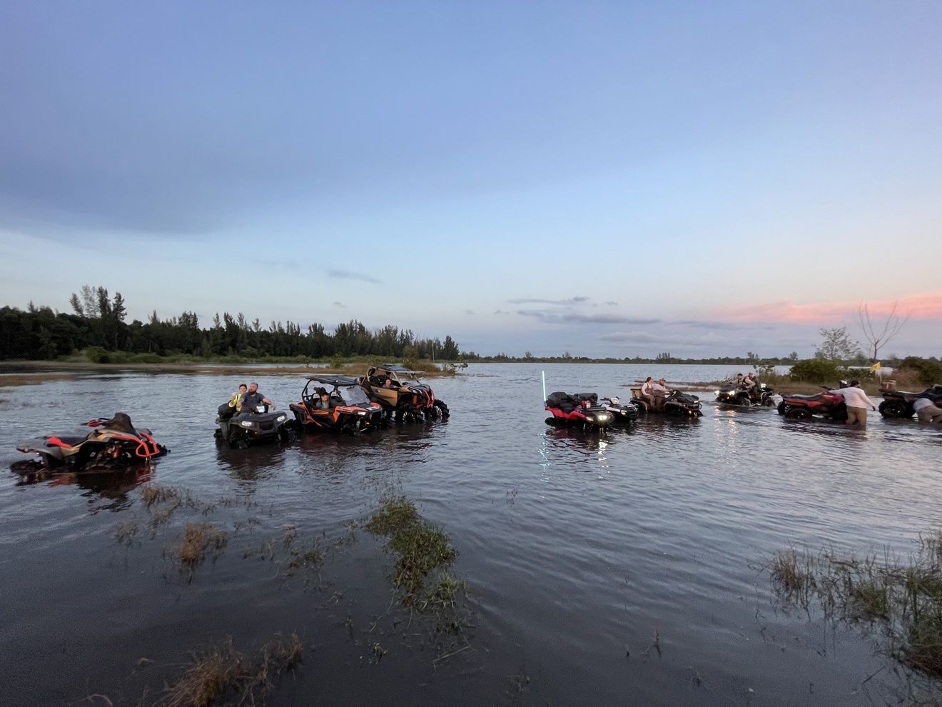 ATVs lined up in the water at sunset