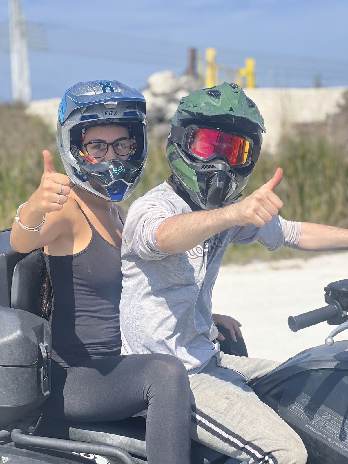Two riders in helmets giving thumbs up on an ATV