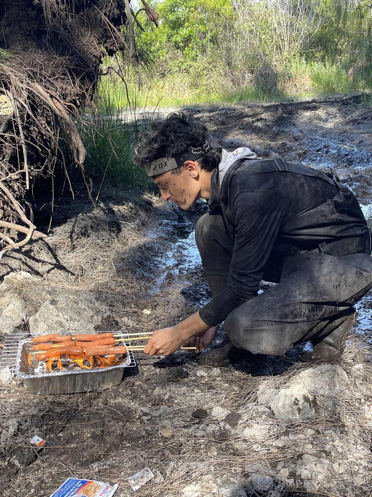 Rider grilling hot dogs on a small trail grill
